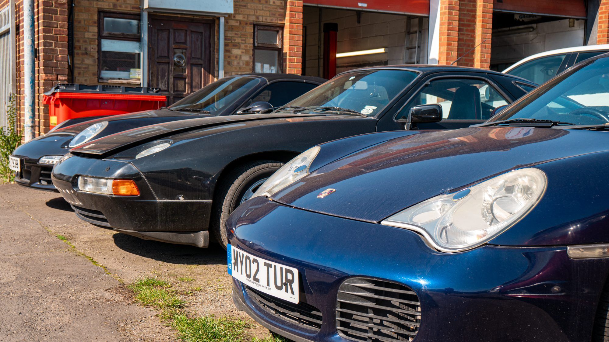 Porsche 928 and Porsche 911 parked outside the workshop