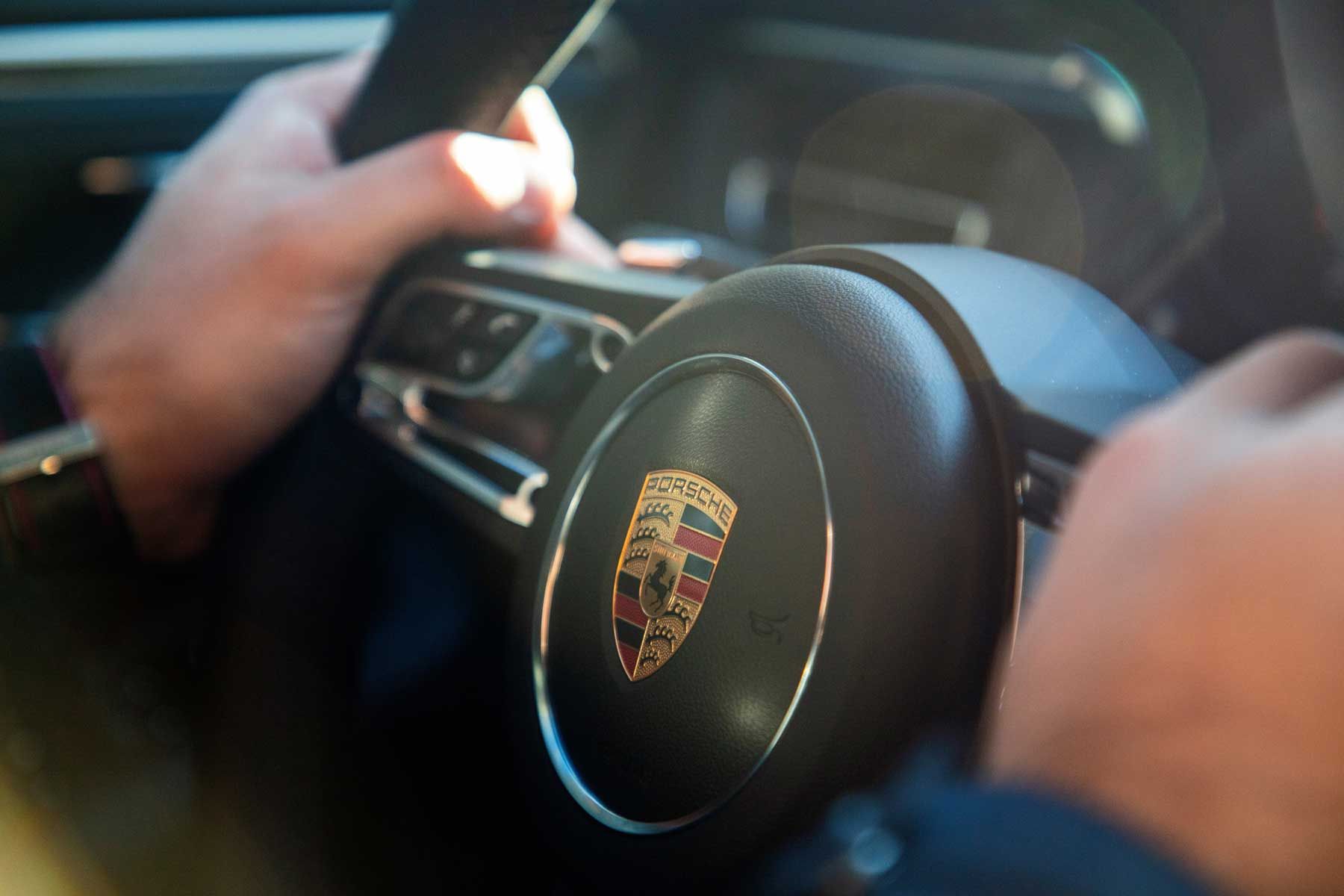 Driver's hands on a Porsche steering wheel